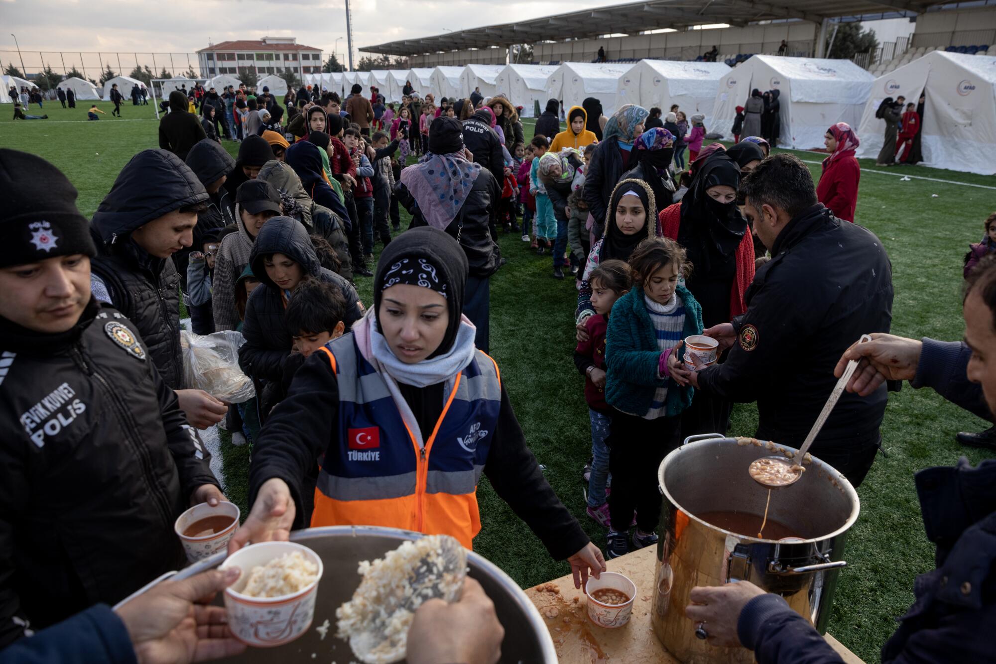 People stand in line for bowls of rice and soup.