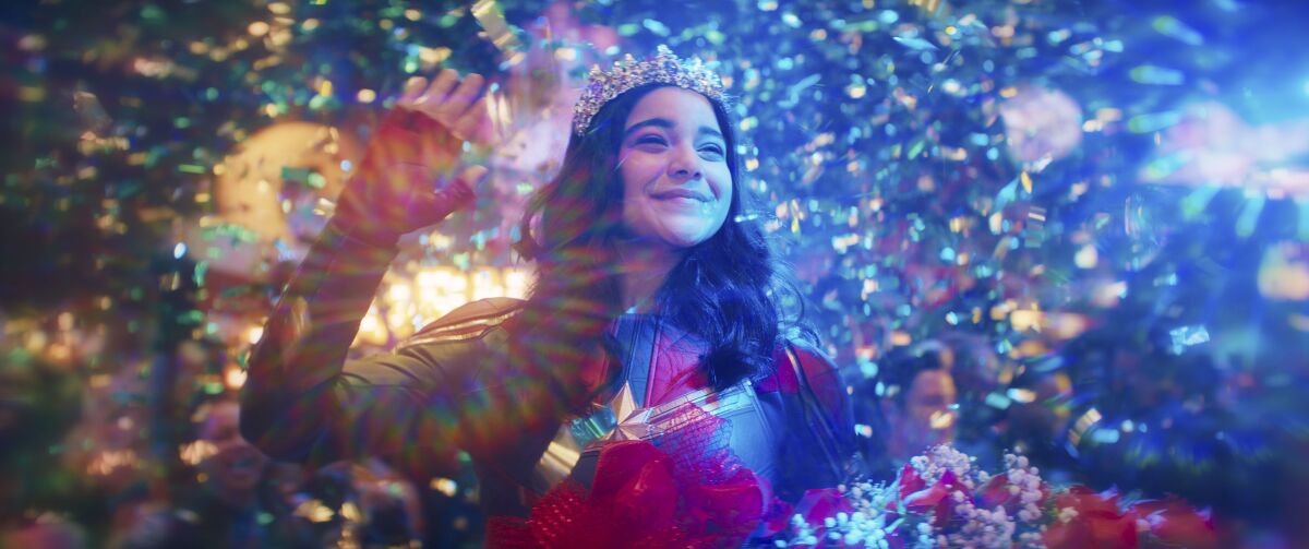A teenage girl in a superhero costume and a tiara waving