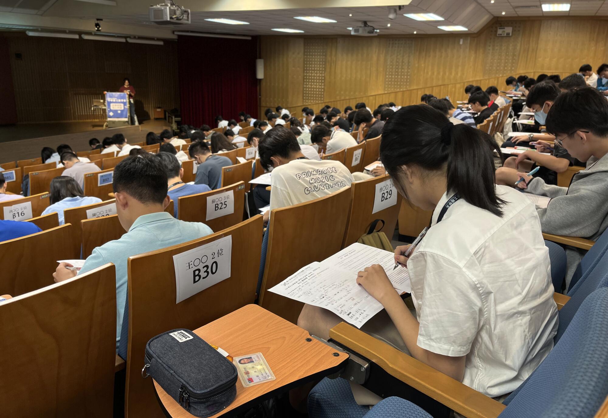 Students taking notes while sitting in an auditorium.
