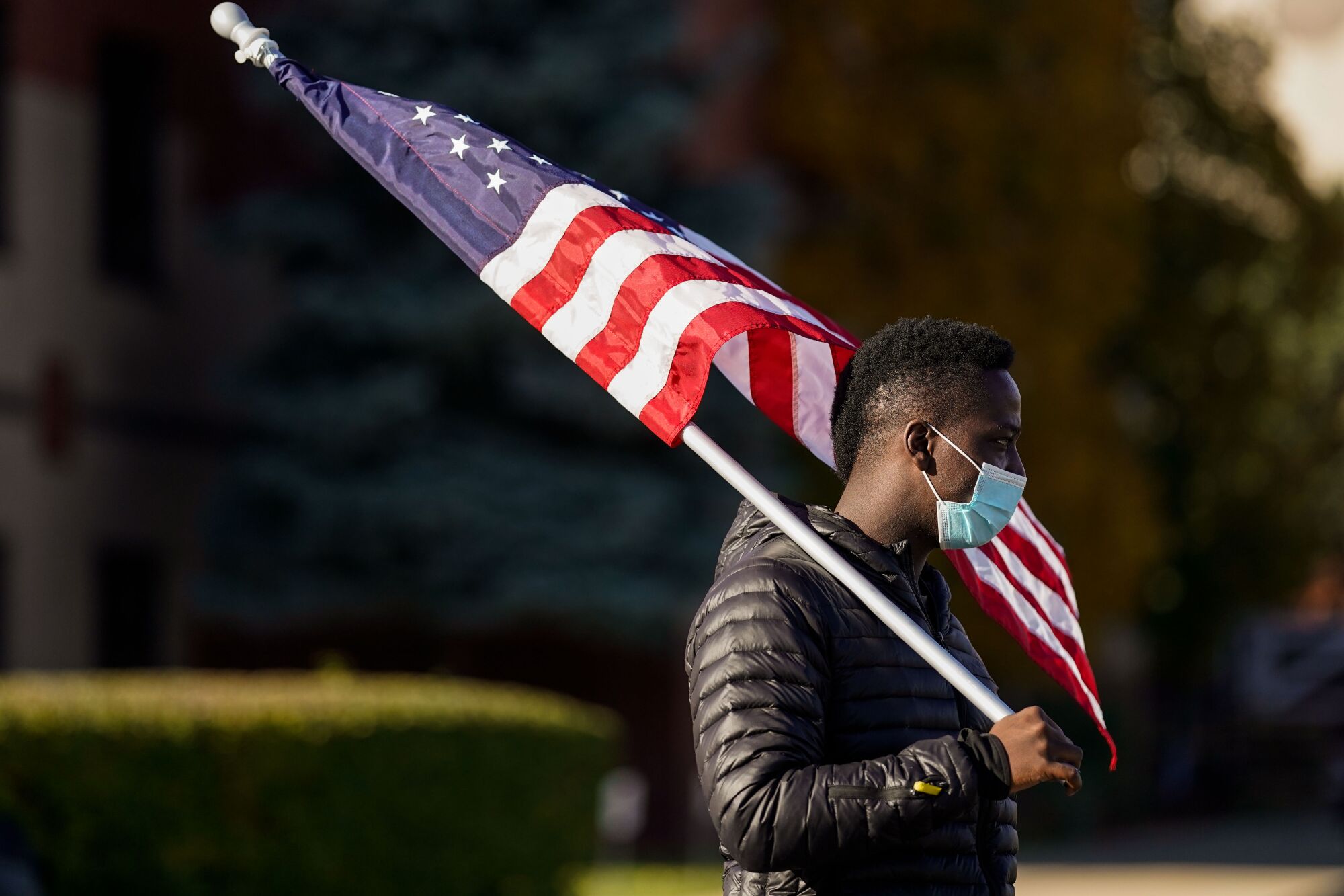 Daniel Billingslea, 27, carries a U.S. flag while canvassing outside the Greater Grace Church polling location in Detroit. 