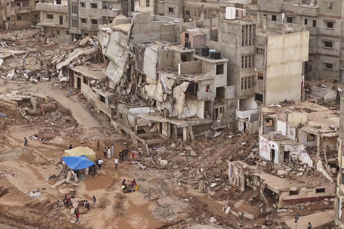 Rescatistas y parientes de víctimas colocan carpas ante edificios derruidos en Derna, Libia, 