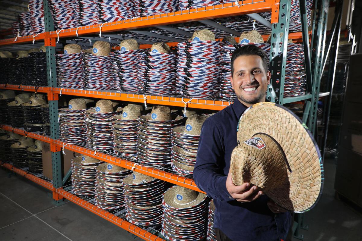 Anthony Lora, founder of the Hemlock Hat Co., at his company's Vista warehouse and headquarters with his hats with their characteristic colorful designs under the brims.