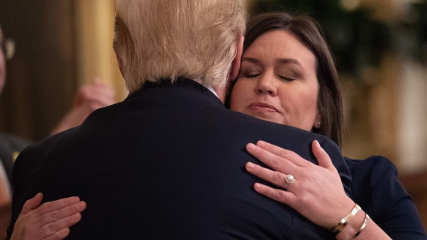 Outgoing White House Press Secretary Sarah Huckabee Sanders hugs President Trump on Thursday in the East Room in Washington.