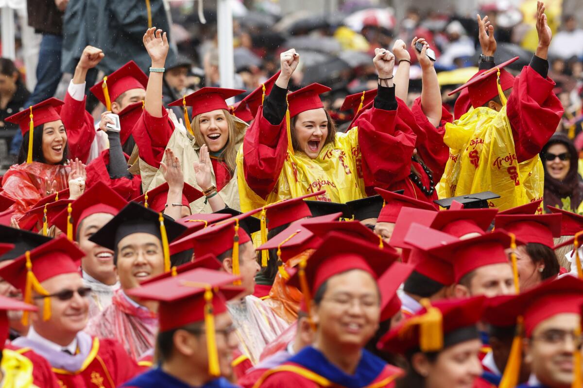 USC graduates wear ponchos over their caps and gowns while cheering in the rain during commencement ceremonies May 15.