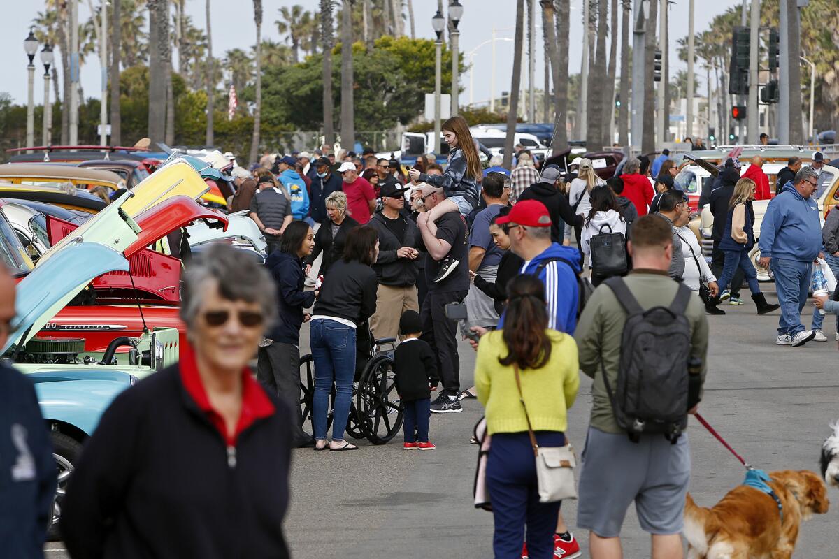 Visitors walk through Pier Plaza during the 20th annual Beachcruisers event on Saturday in Huntington Beach.