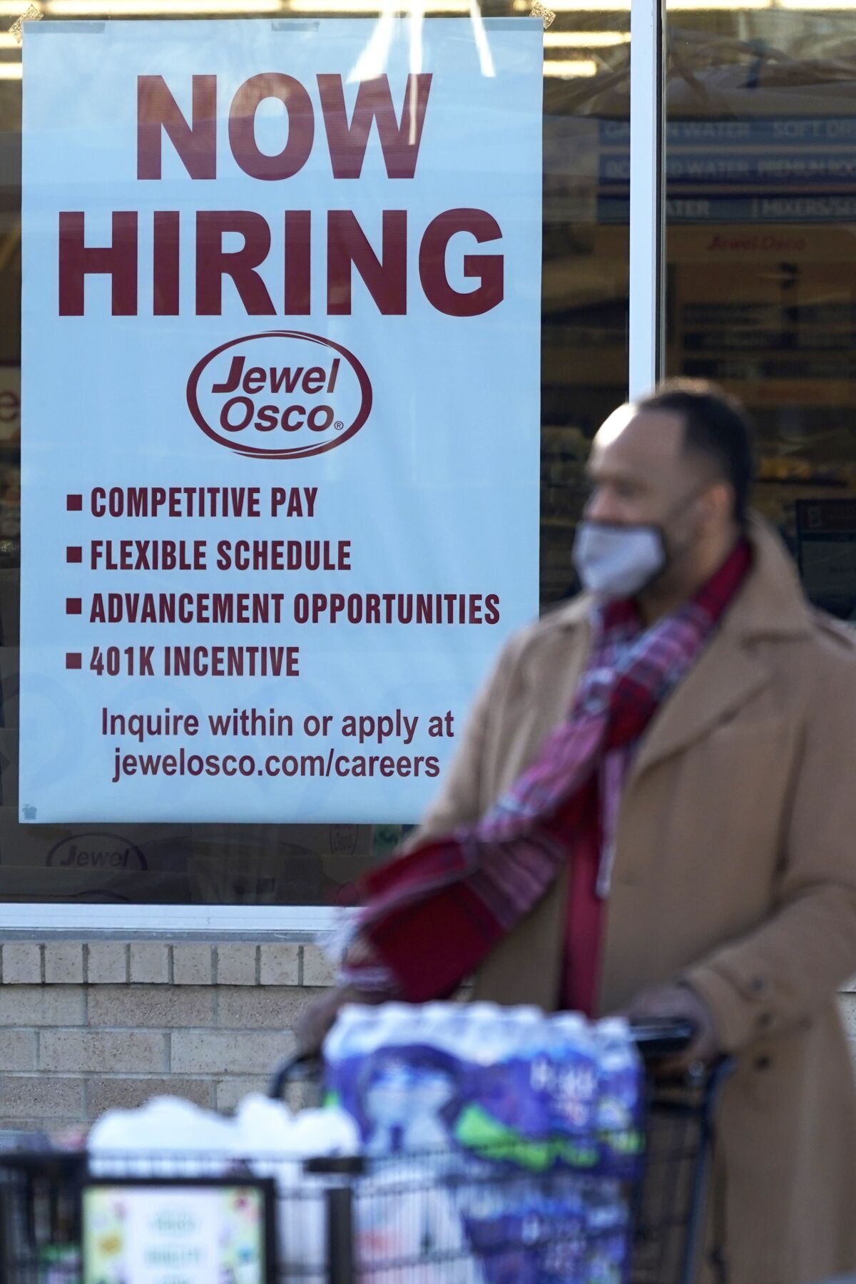 A now-hiring sign is shown as a shopper exits a grocery store Dec. 4 in Deerfield, Ill.