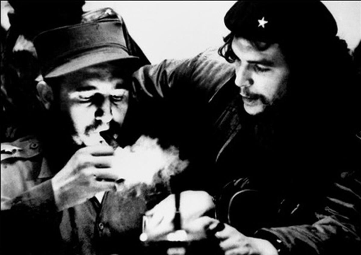 Fidel Castro lights a cigar while listening to Argentine revolutionary Ernesto "Che" Guevara in this undated photo from the 1960s.