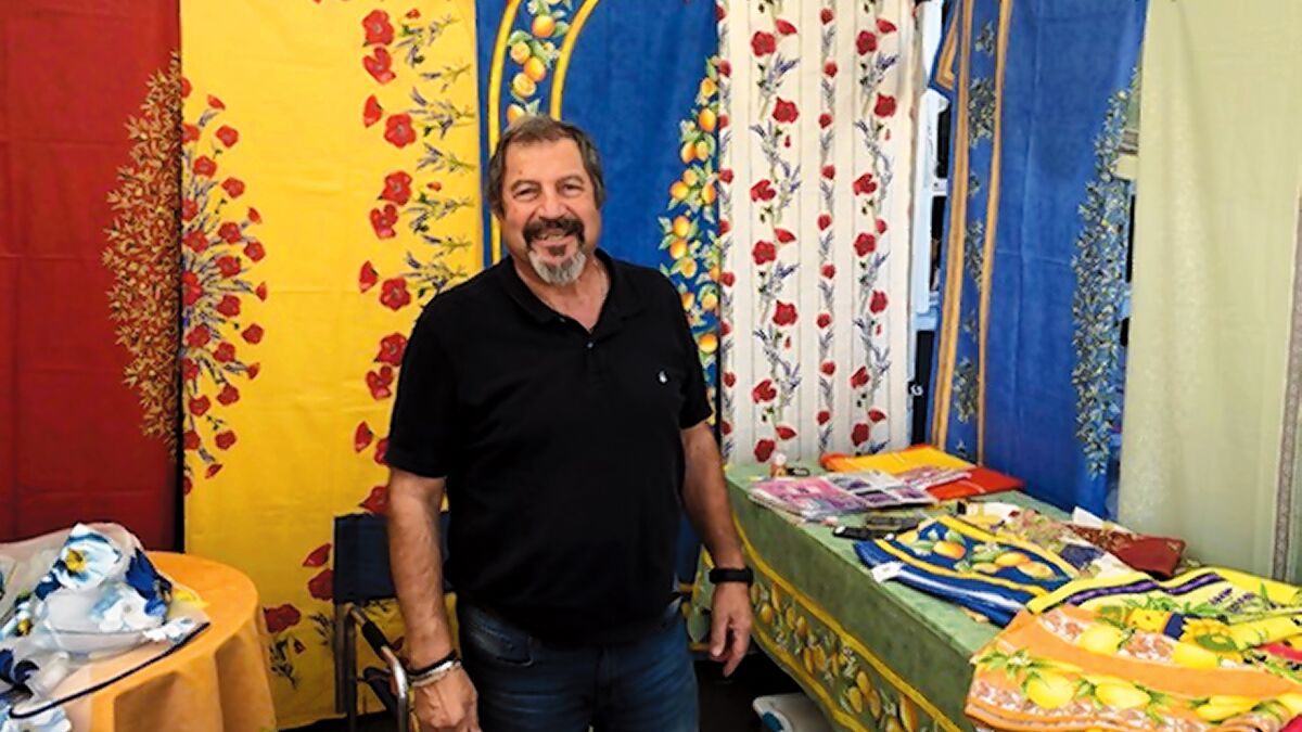 Khosrow Behzadi sells tablecloths and other items from Provence, France, at La Jolla Open Aire Market, which is held Sundays, 9 a.m.-1 p.m. at 7335 Girard Ave. in La Jolla, at the corner of Girard Avenue and Genter Street. lajollamarket.com