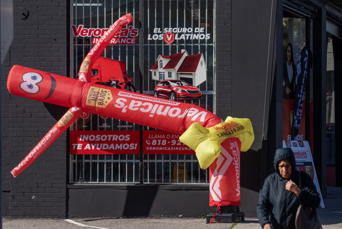 A plastic wind dancer contorts during in wind while a person walks nearby