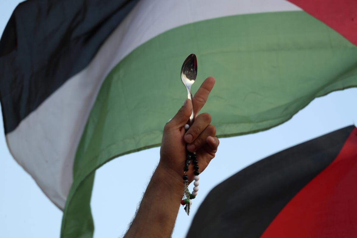 A protester holds a Palestinian flag and a spoon, which has become a symbol celebrating the six Palestinian prisoners who recently tunneled out of Gilboa Prison, in Umm el-Fahm, Israel, Friday, Sept. 10, 2021. (AP Photo/Ariel Schalit)