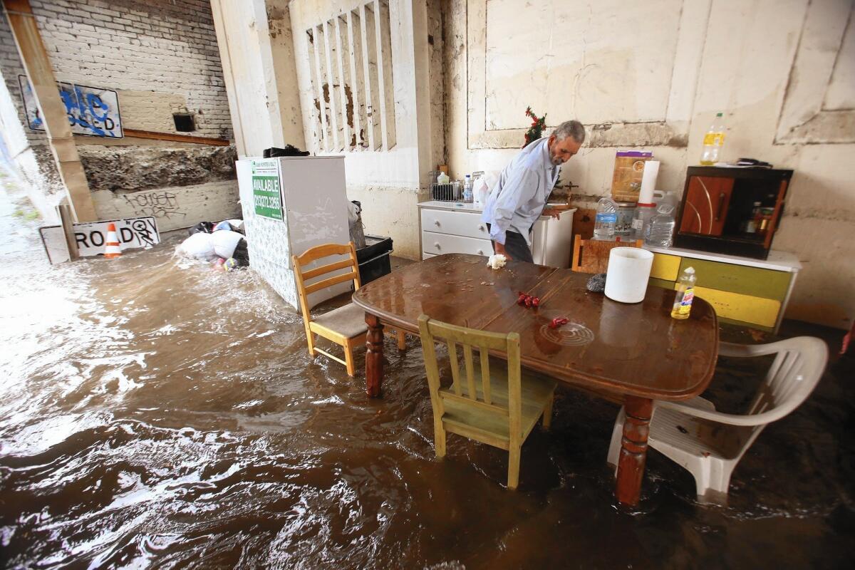 Felipe Flores Lopez, 59, tries to secure his homeless encampment as water begins to flood Avenue 26 under the Cypress Park/Lincoln Heights Gold Line Station in Lincoln Heights.