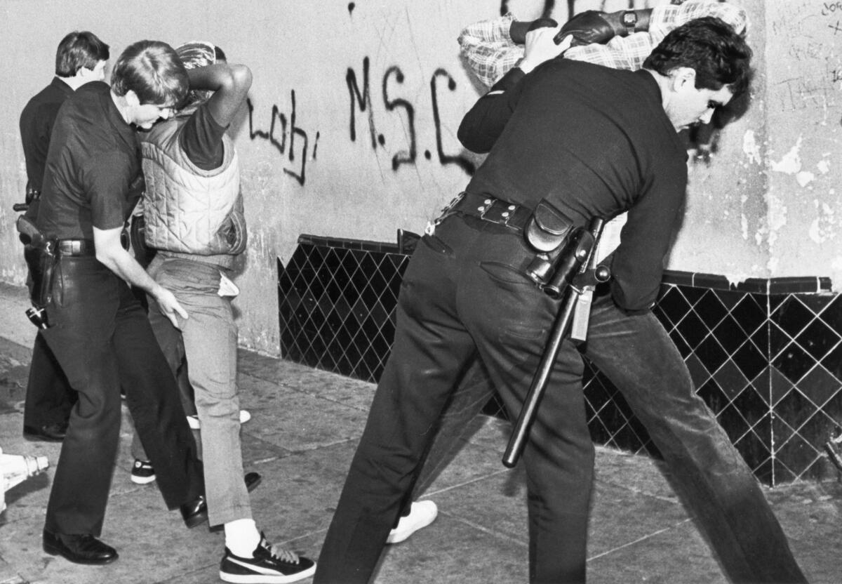 Police search young men during a sweep in South Los Angeles in 1985.