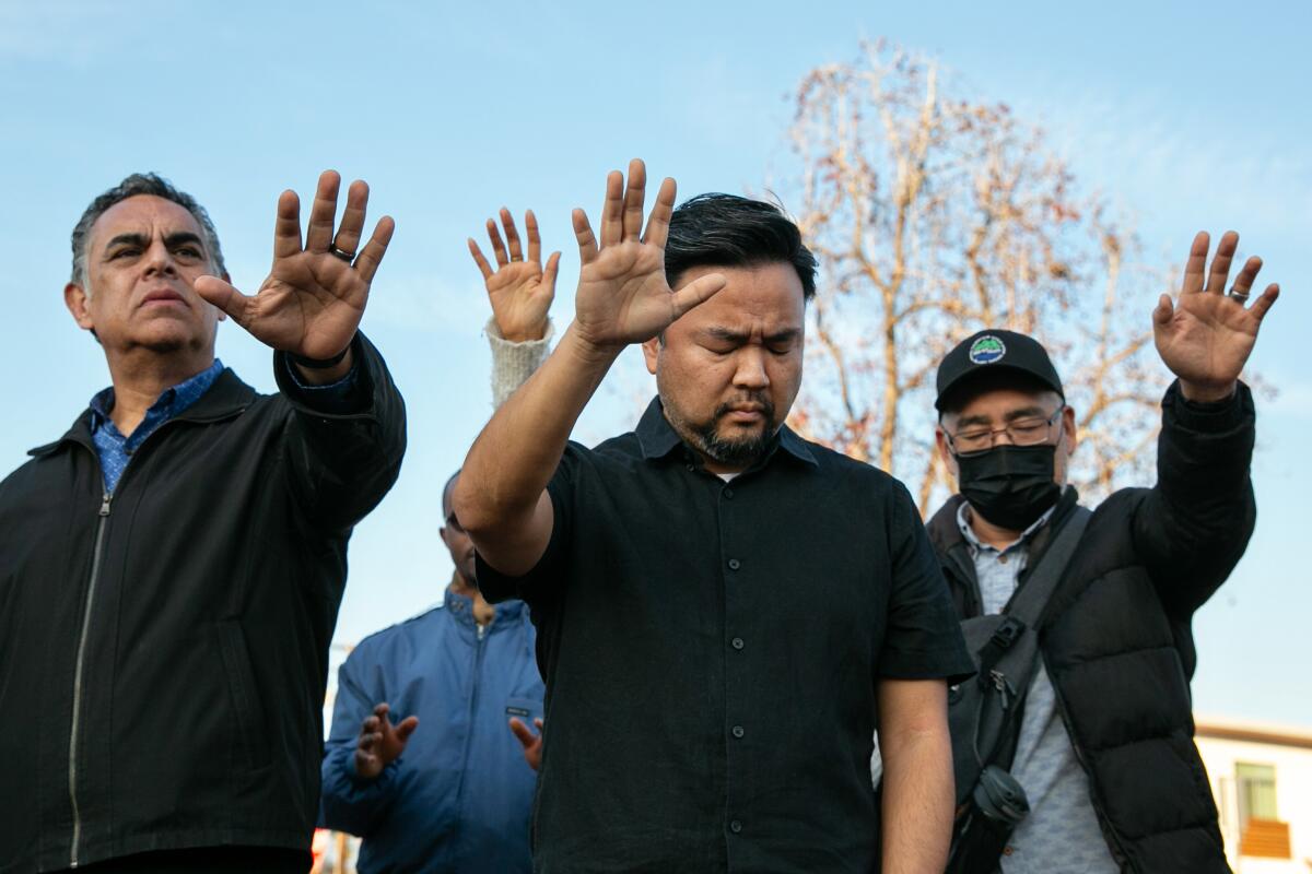 Men hold up their hands during a vigil for Monterey Park shooting victims.
