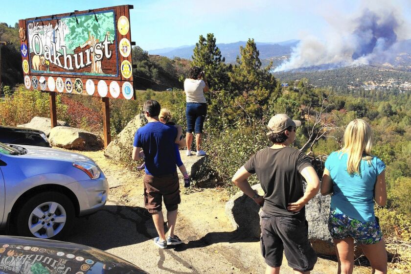 People watch a fire burning from the California 41 overlook on the way north into Oakhurst, Calif.