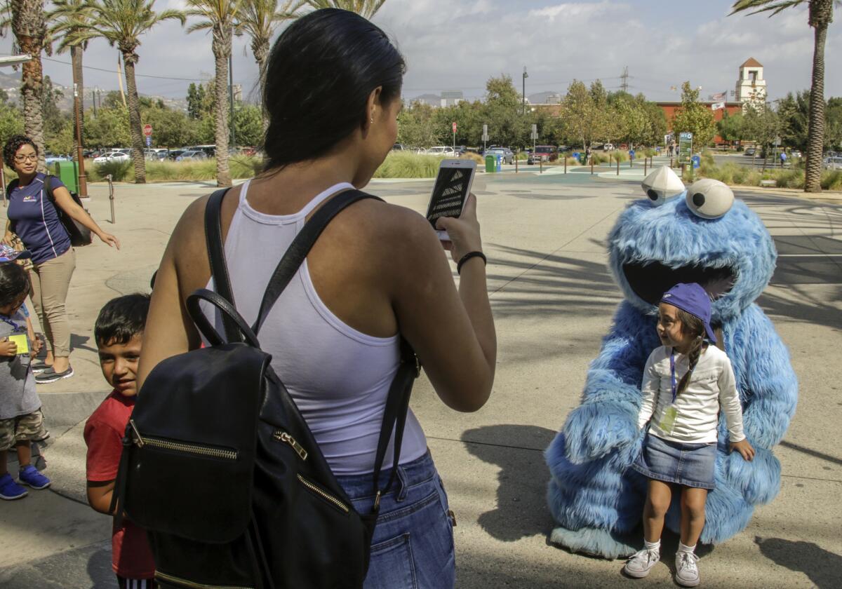 Stephanie Bahena takes a photo of her daughter with Adam Sandler dressed as Cookie Monster outside the Los Angeles Zoo.