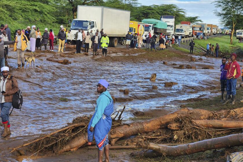 People gather on the main road after a dam burst, in Kamuchiri Village Mai Mahiu, Nakuru County, Kenya, Monday, April 29, 2024. Police in Kenya say at least 40 people have died after a dam collapsed in the country's west. (AP Photo)