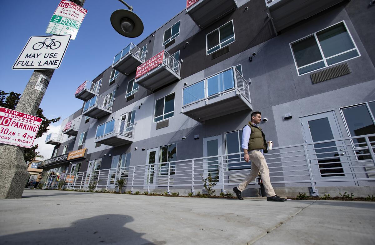 A man walks past a large apartment complex in Los Angeles. 