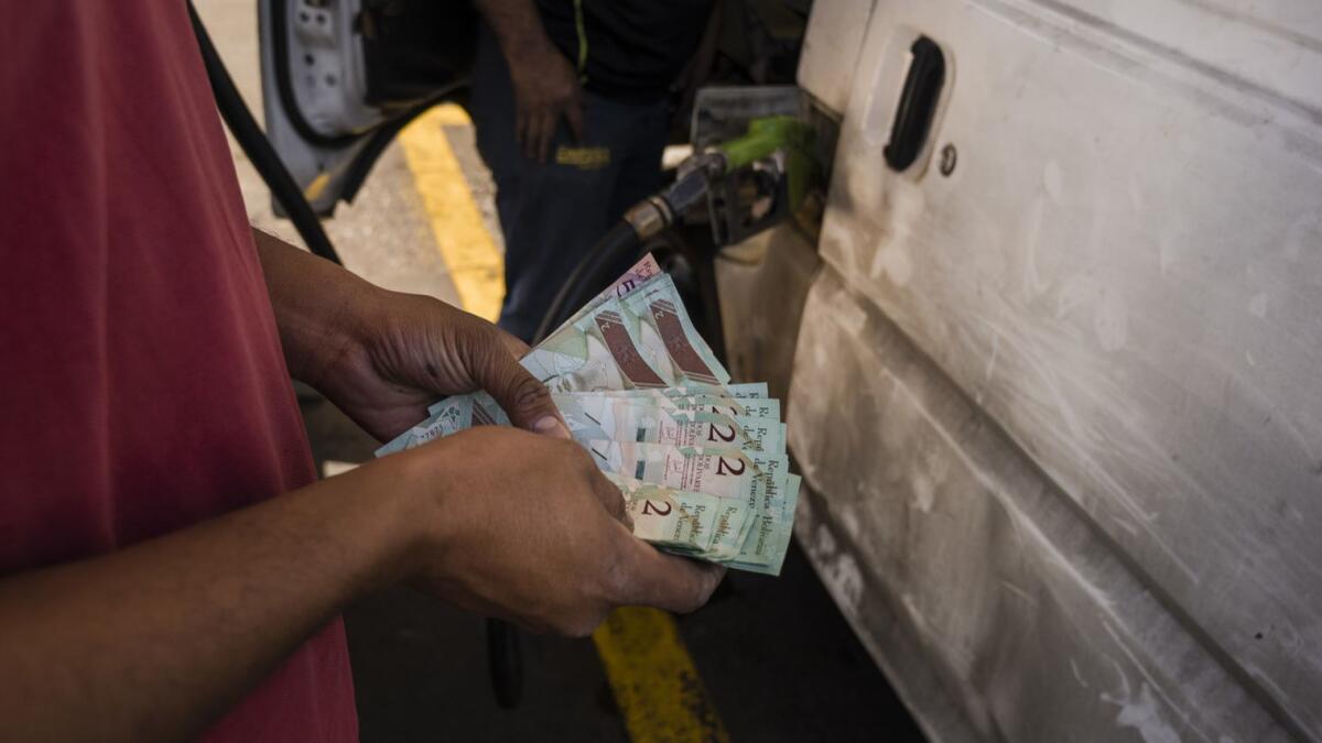 A Caracas gas station worker gives change to a customer.