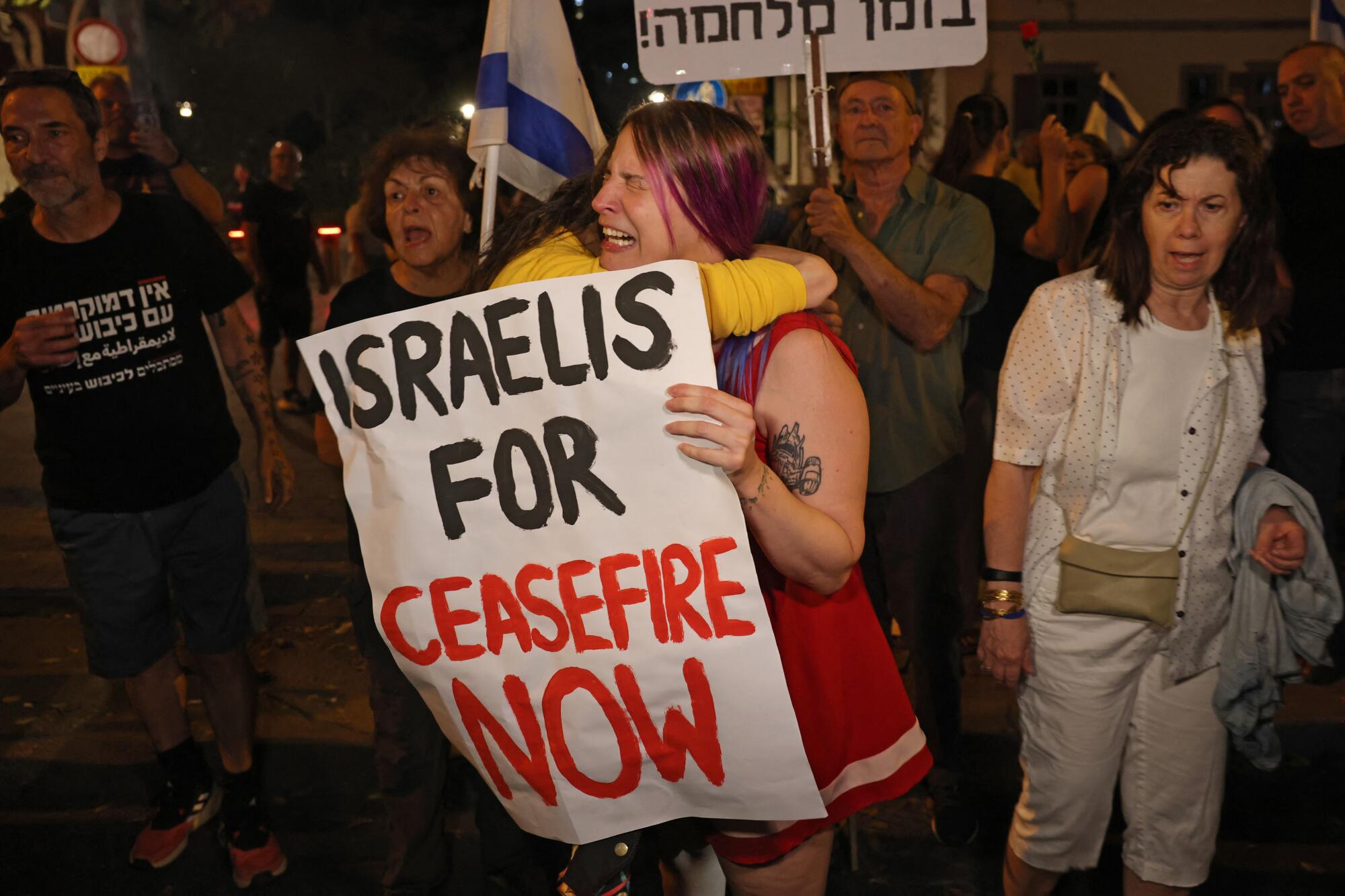 Israeli left-wing activists hold placards and chant slogans during a demonstration calling for a cease-fire.