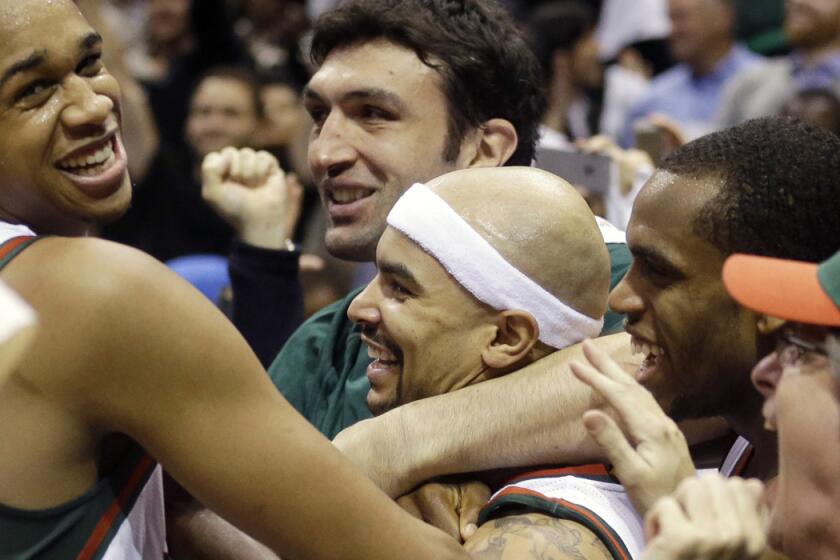 Milwaukee's Jerryd Bayless, center, is swarmed after making the game-winning basket Saturday against Chicago.