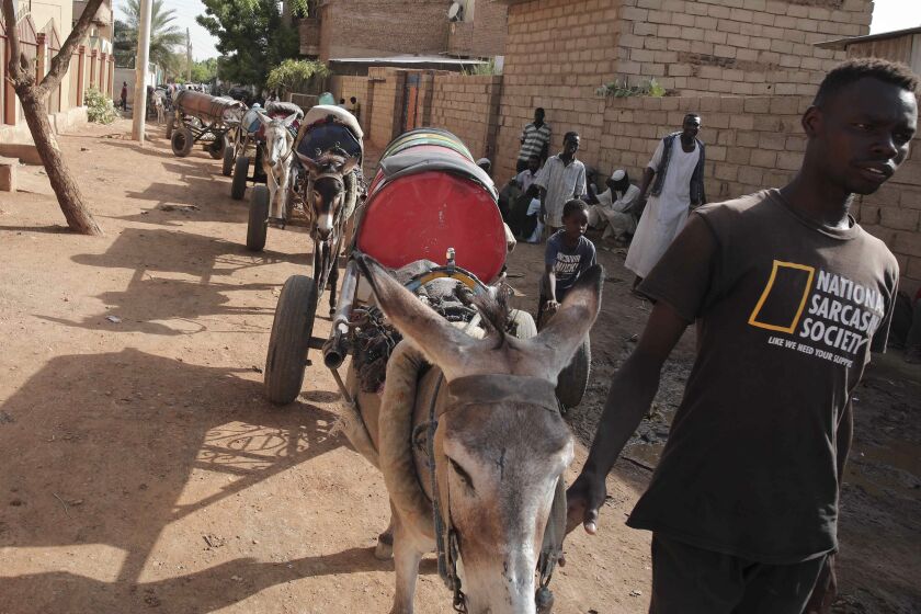 A man leads donkeys pulling water barrels in Khartoum, Sudan, Sunday, May 28, 2023. The Sudanese army and a rival paramilitary force, battling for control of Sudan since mid-April, had agreed last week to the weeklong truce, brokered by the U.S. and the Saudis. However, the cease-fire, like others before it, did not stop the fighting in the capital of Khartoum and elsewhere in the country. (AP Photo/Marwan Ali)