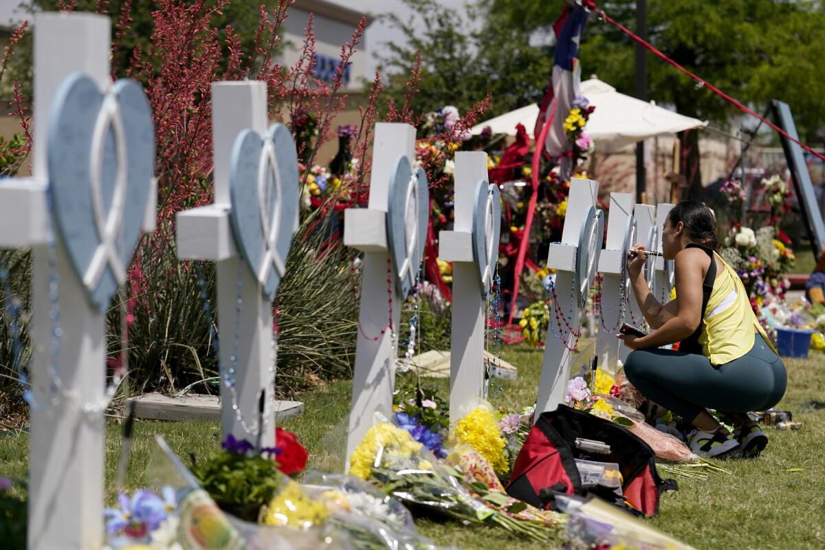 Una mujer firma una cruz alineada junto a otras en un altar improvisado en honor de las víctimas 