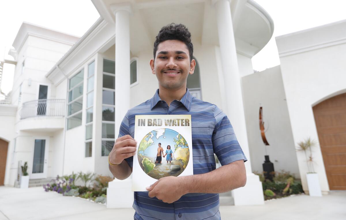 Arjun Vij, 18, a senior at Corona del Mar High, holds a copy of his self-published book “In Bad Water.”