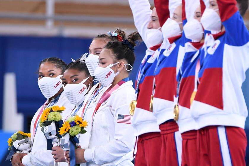 -TOKYO,JAPAN July 26, 2021: USA's Simone Biles, second from left, watches the ROC team celebrate their gold medal in the women's team final at the 2020 Tokyo Olympics. (Wally Skalij /Los Angeles Times)