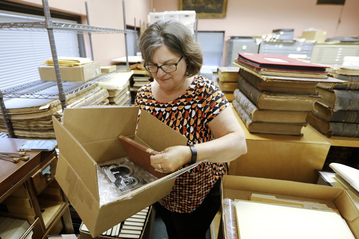 A woman pulls an overdue book from a shipping box.