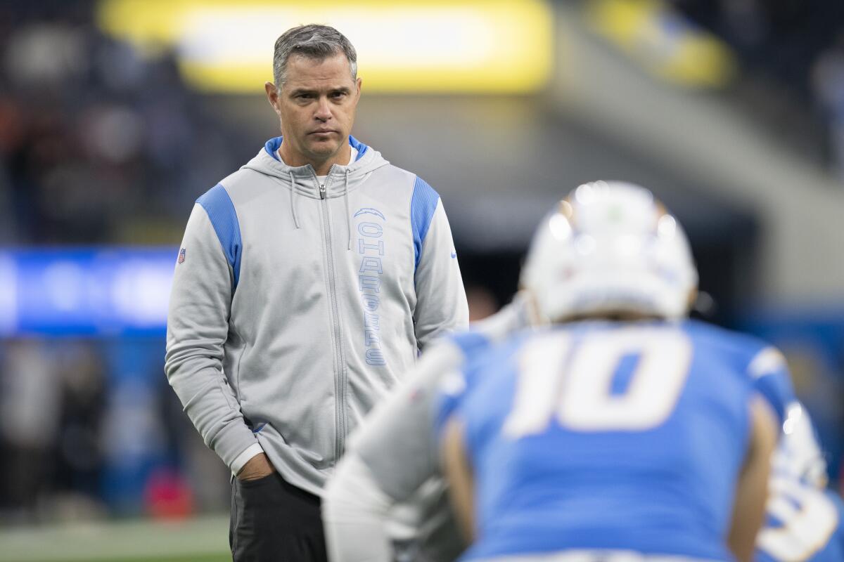 Chargers offensive coordinator Joe Lombardi watches quarterback Justin Herbert warm up.