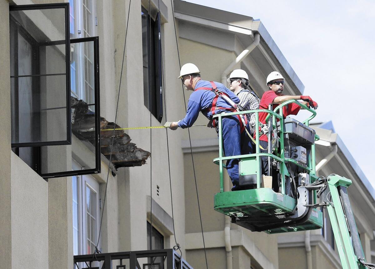 Crew members measure the remaining wood from a balcony that collapsed from the fifth floor of the Library Gardens apartment complex in Berkeley.