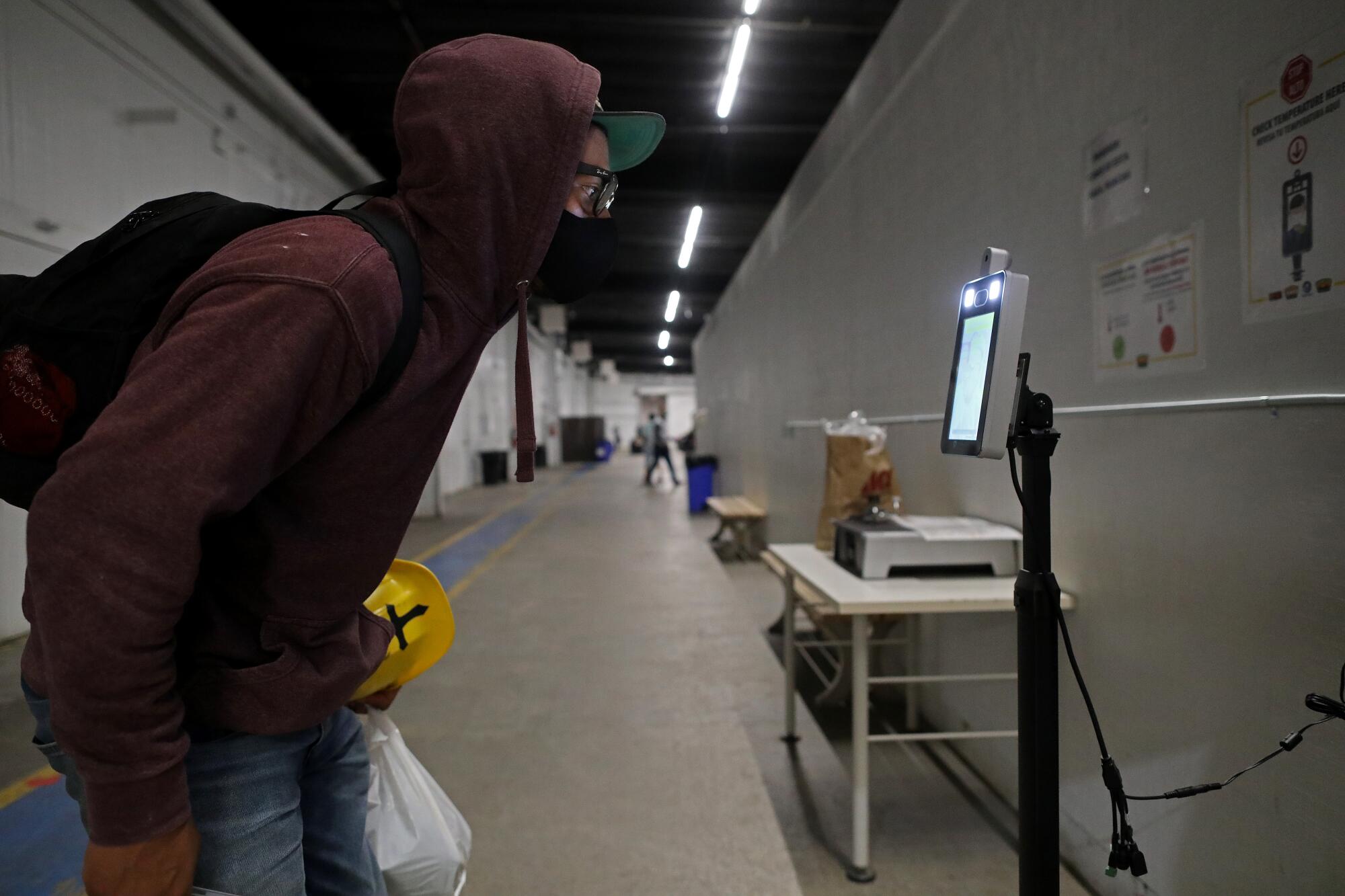 A farmworker checks his temperature when entering and exiting Fresh Harvest's dormitories