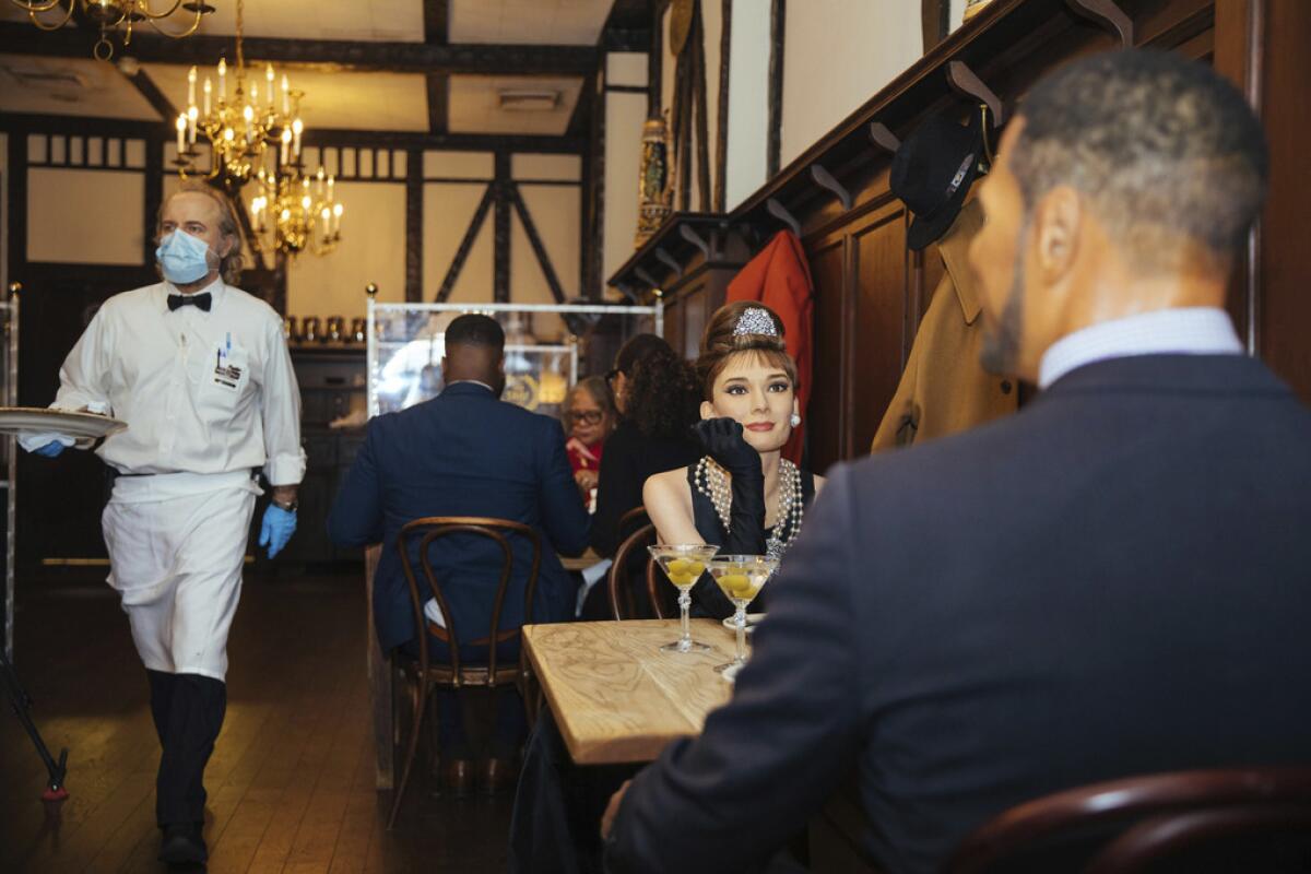 Wax statues of Audrey Hepburn and Michael Strahan sit in Peter Luger Steakhouse in New York. 