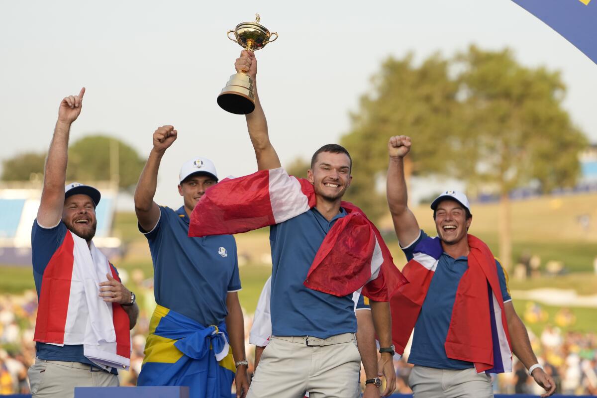 Europe's Nicolai Hojgaard lifts the Ryder Cup trophy while celebrating with teammates on Sunday.