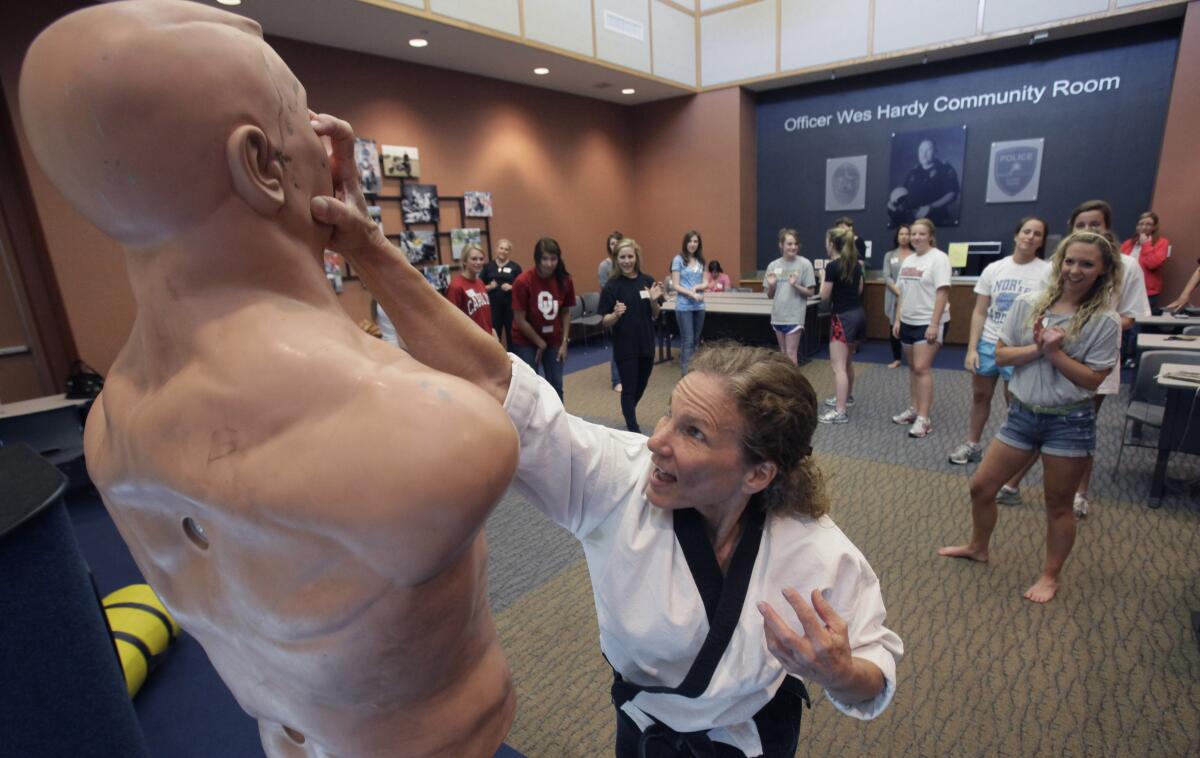 A teacher uses a dummy to show female students how to jab fingers into the eyes of an attacker.