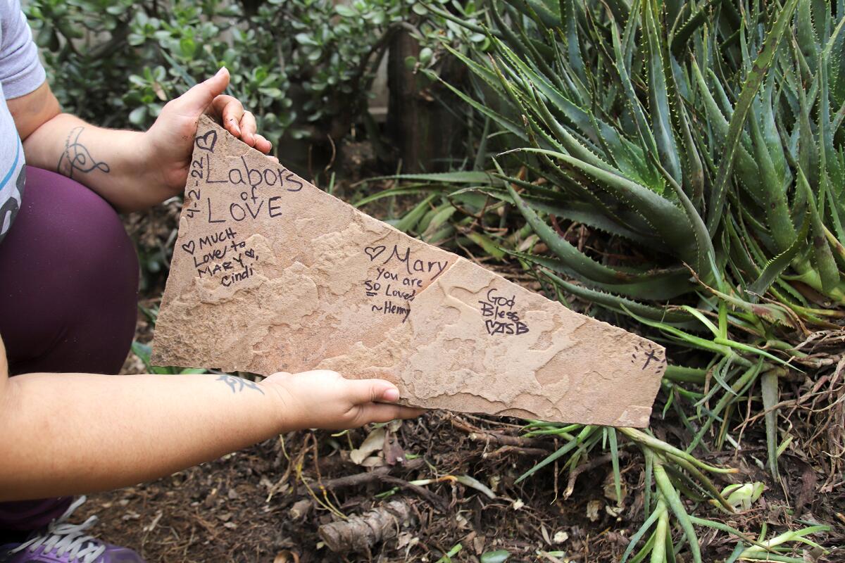 Henny Abraham from Labors of Love places a "love rock" in the garden for Costa Mesa homeowner Mary Parpal on Saturday.