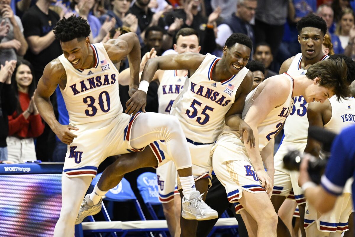 Kansas guard Ochai Agbaji (30), guard Jalen Coleman-Lands (55) and forward Zach Clemence (21) celebrate after defeating Texas during overtime in an NCAA college basketball game in Lawrence, Kan., Saturday, March 5, 2022. (AP Photo/Reed Hoffmann)