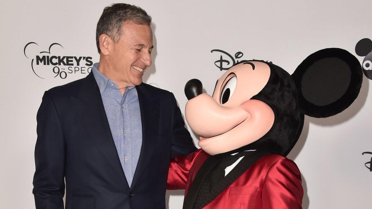Disney CEO Bob Iger smiles at Mickey Mouse at a Saturday event.