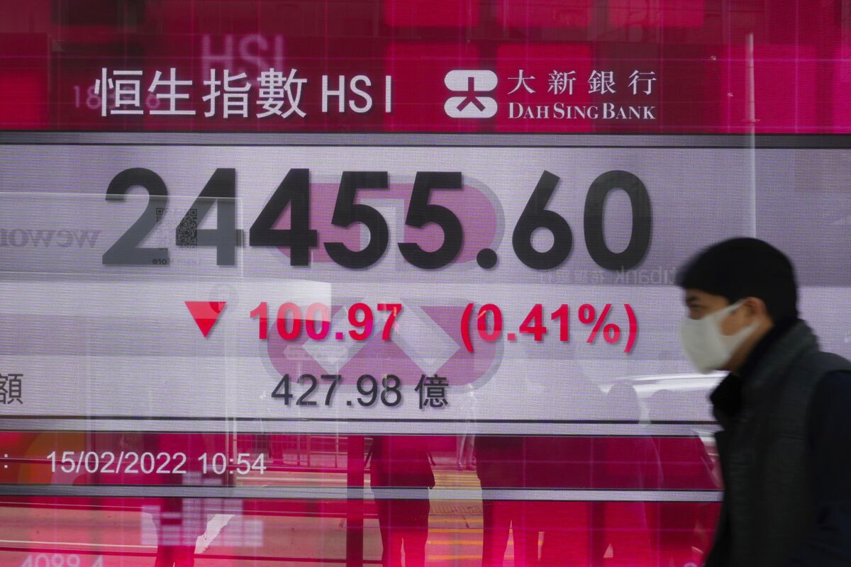A man walks past a bank's electronic board showing the Hong Kong share index in Hong Kong Tuesday, Feb. 15, 2022. Asian shares were mostly lower Tuesday, echoing a decline on Wall Street, amid concerns about rising tensions in Ukraine over the thousands of Russian troops that have been amassing on the border. (AP Photo/Vincent Yu)