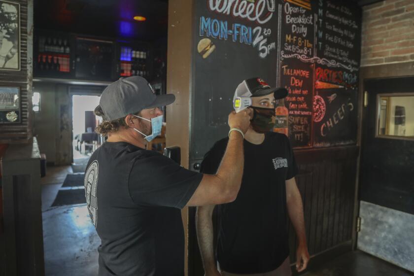 LAKESIDE, CA - SEPTEMBER 24: Owner Ben Clevenger (left) takes the temperature of manager/lead bartender Curtis Schussler before he starts his shift at Eastbound Bar and Grill on Thursday, Sept. 24, 2020 in Lakeside, CA. (Eduardo Contreras / The San Diego Union-Tribune)