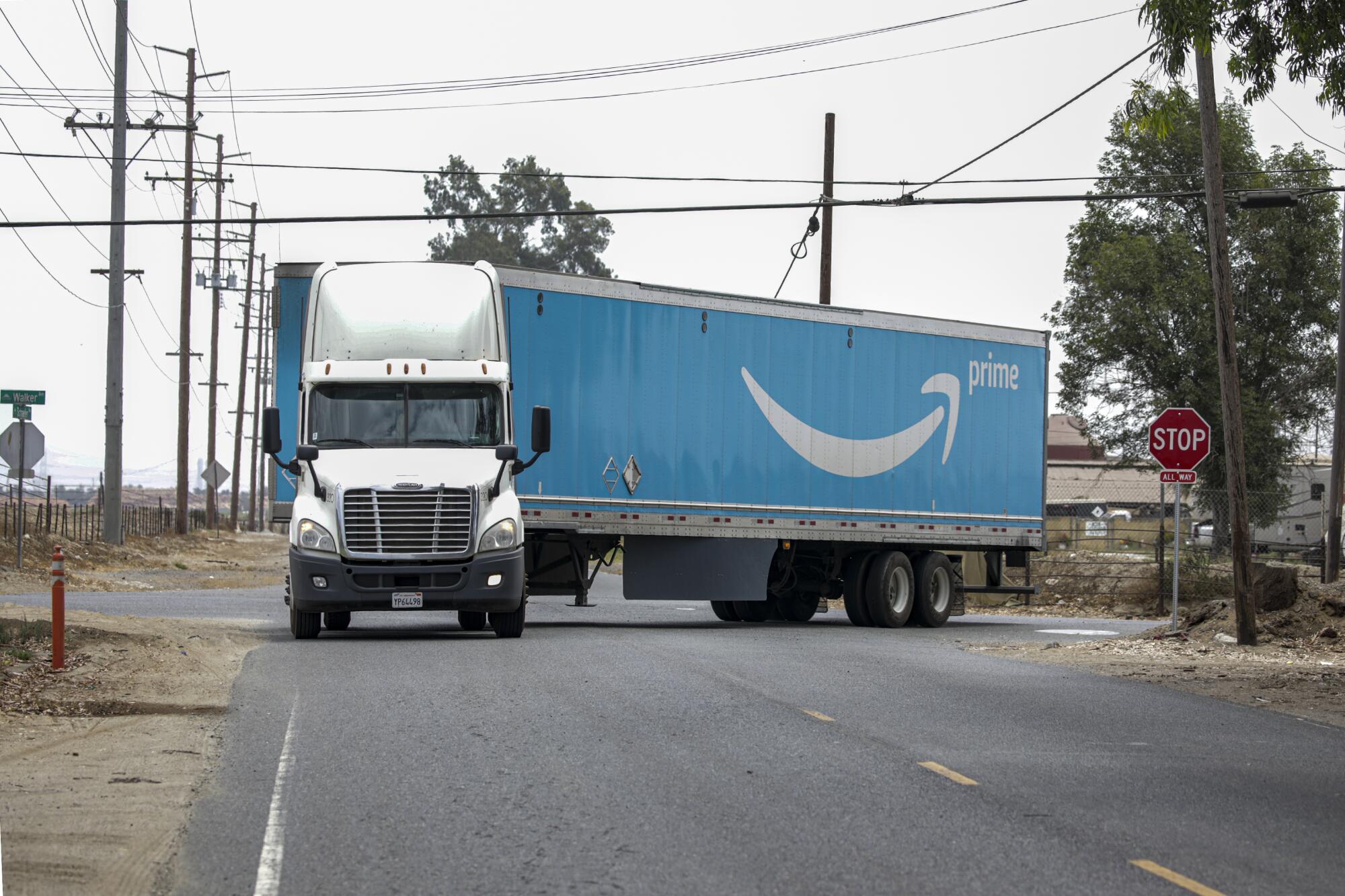 An Amazon truck negotiates a sharp turn on a road.