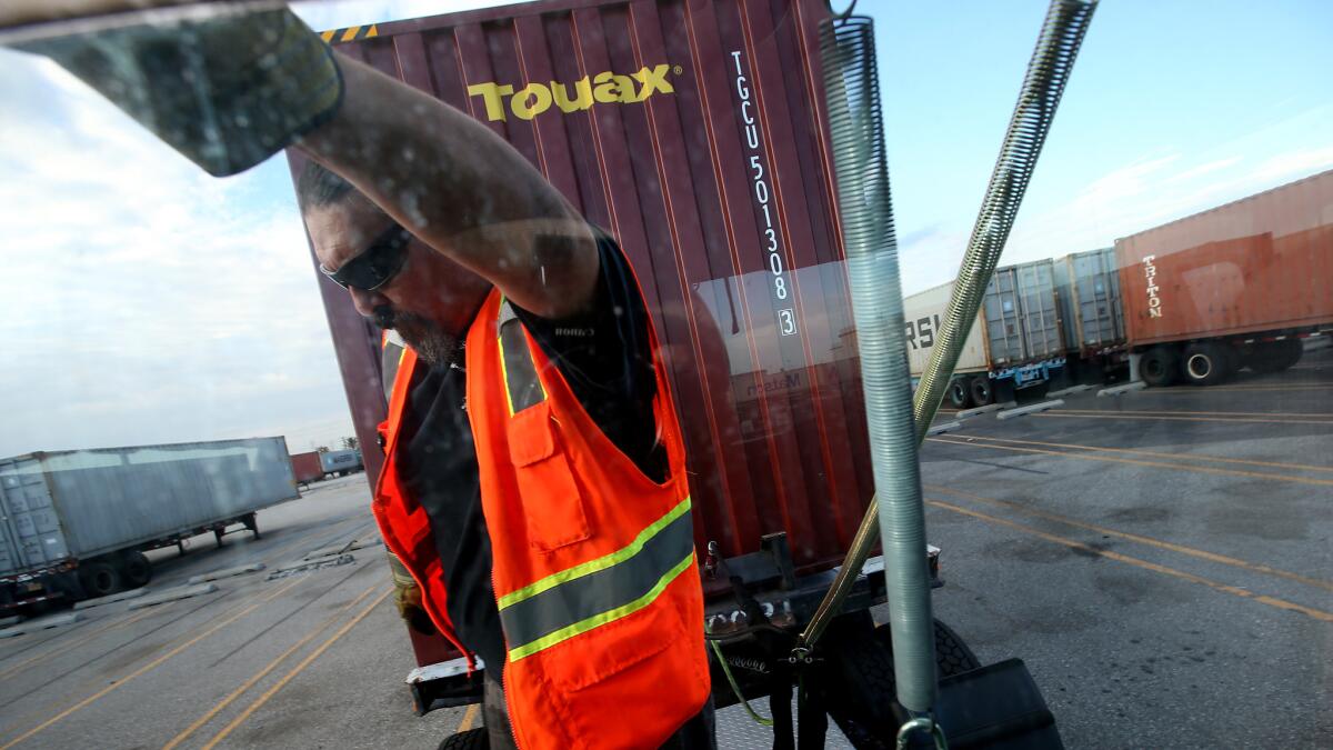 Driver Scott Spindola hooks up a trailer to his big rig truck at the Shippers Transport Express yard in Carson.