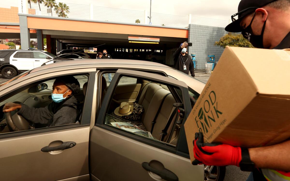 A volunteer loads donated food into a car at Baldwin Hills Crenshaw shopping center.