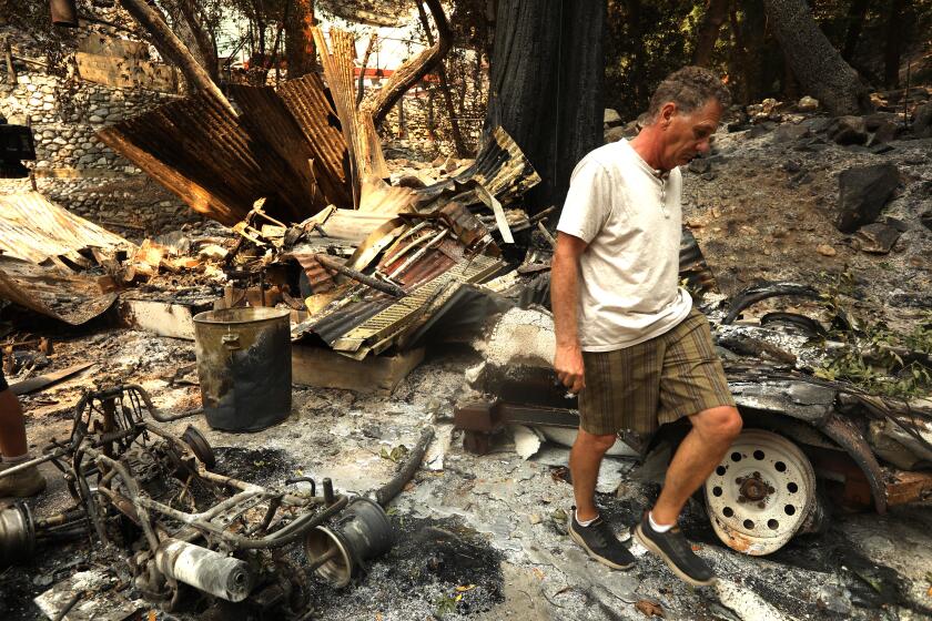 MOUNT BALDY, CA - SEPTEMBER 12, 2024 - Paul Faulstick, 67, walks among the ruins of his friend, David Mix's, property that was destroyed in the Bridge fire along Bear Canyon Road in Mount Baldy on September 12, 2024. " "It was Armageddon-like," said David Mix, 50, about the fire. This place is like a relative. I had to know if she was gone," Mix concluded. (Genaro Molina/Los Angeles Times)