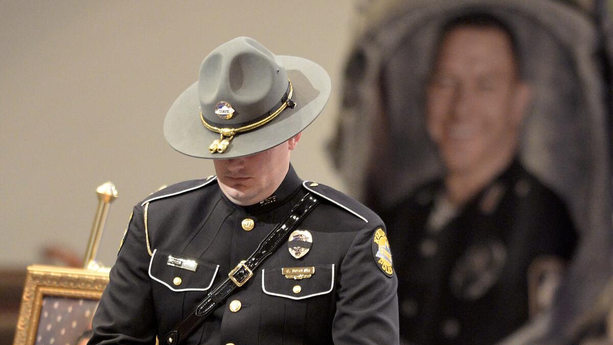 A Kentucky State Police officer stands as part of the honor guard during the funeral service for Bardstown, Ky., Officer Jason Ellis in May 2013.