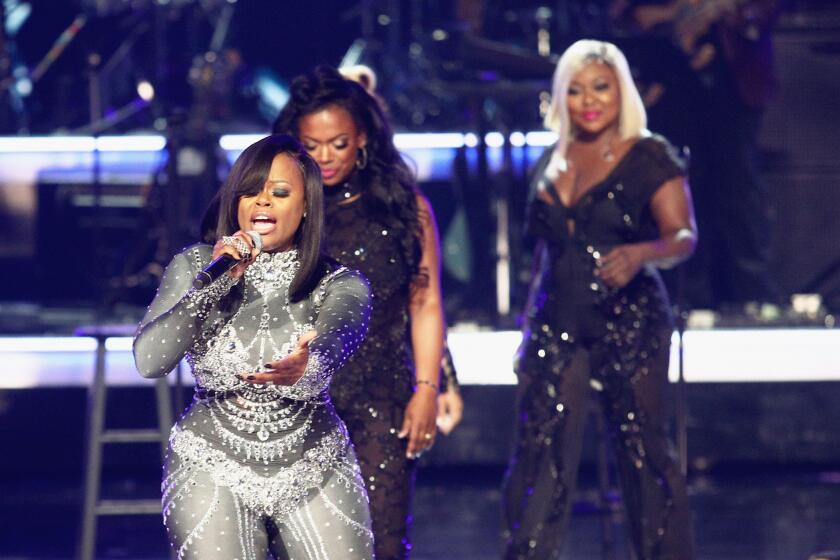Three women performing onstage in sparkly outfits