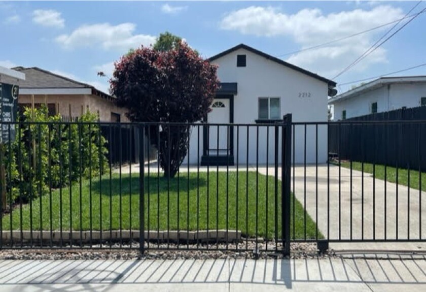 A white house with trim and a metal gate.