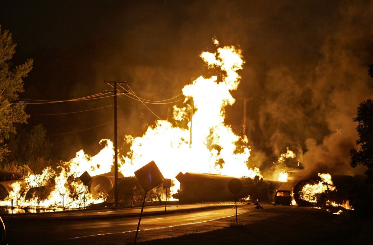 In this 2009 file photo, a car at right is engulfed in flames after colliding with rail cars loaded with ethanol that derailed in Rockford, Ill. The Obama administration has proposed rules to improve oil train safety.