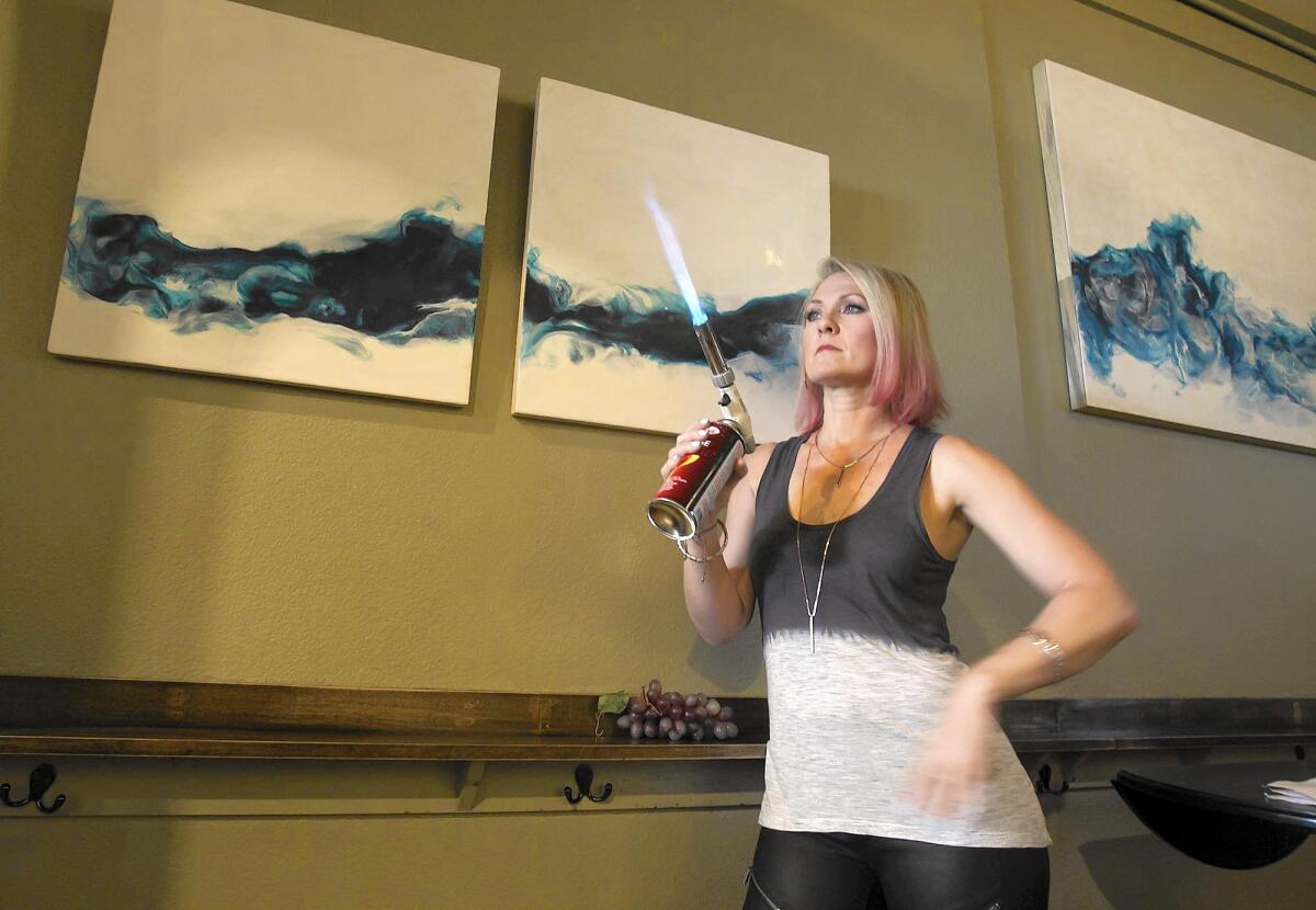 Artist Heather Miller uses a blowtorch to create works made of fire and molten wax. Miller is currently having a show at Anne's Boutique Wines in Costa Mesa.