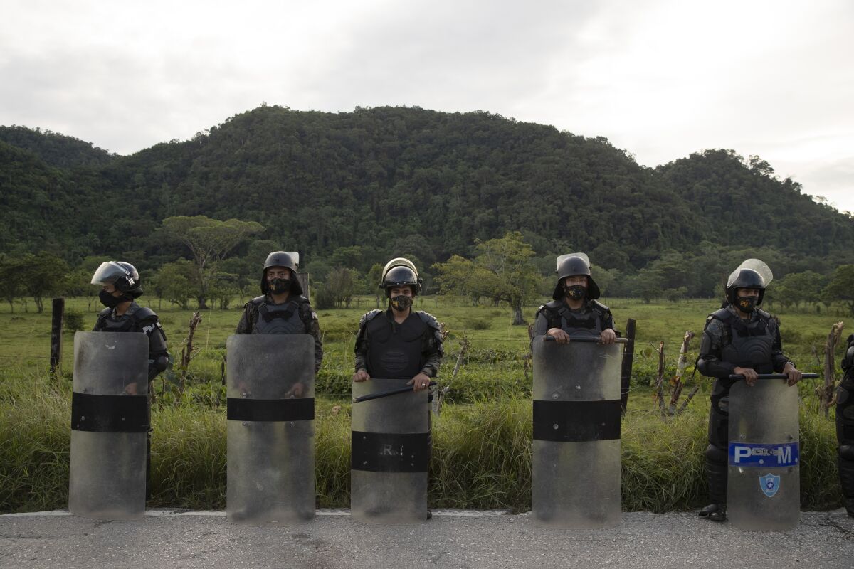 Security forces block Honduran migrants in San Luis Peten, Guatemala, Saturday, Oct. 3, 2020. Early Saturday, hundreds of migrants who had entered Guatemala this week without registering were being bused back to their country's border by authorities after running into a large roadblock. (AP Photo/Moises Castillo)